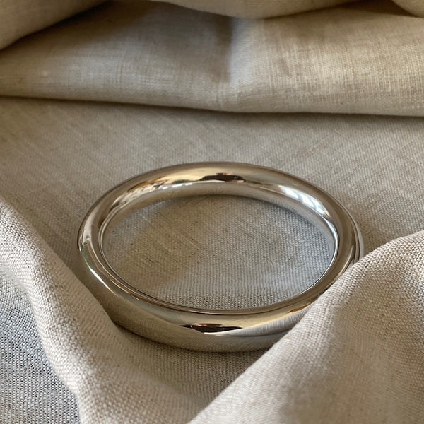 Chubby Sterling Silver hollow bangle sits on linen